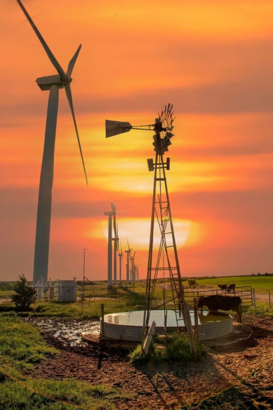 Independent Water Pumping: Efficient & Reliable Solutions. A modern wind turbine and a vintage windmill standing side by side against a sunset sky