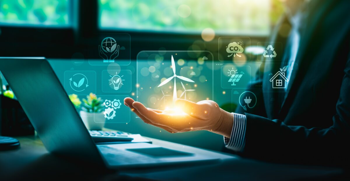 Person holding a wind turbine icon in hand with symbols of sustainable energy and eco-friendly technology