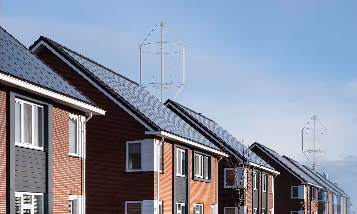 Reihenhäuser mit Solarpaneelen und kleinen Windturbinen auf den Dächern, die ein Mikronetzsystem für private Haushalte darstellen.